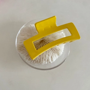 Close-up of bright yellow matte geometric hair claw clip with rectangular cutout frame