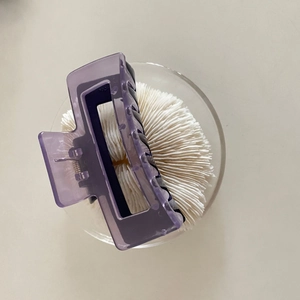 Detailed top view of a large translucent purple resin hair claw clip on a white plate