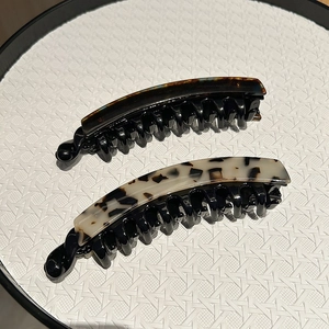 Banana hair clips with tortoise shell and marble patterns on a white display plate