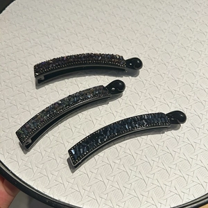 Détail de pinces à cheveux banane avec strass scintillants aux reflets violets et bleus