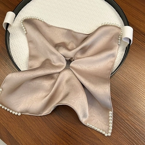 Détail du satin de couleur champagne avec bordure en perles et texture soyeuse élégante