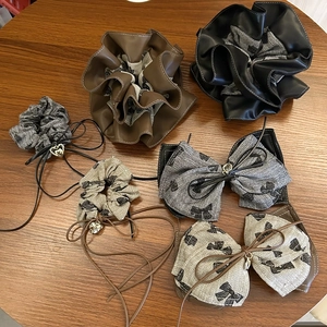 Close-up of PU leather scrunchies and tweed bow clips with heart pendants on wood