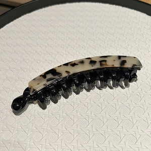 Close-up of acetic acid hair banana clip featuring white leopard pattern and black comb teeth