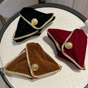 Close-up of velvet headbands in burgundy and black with gold crest buttons