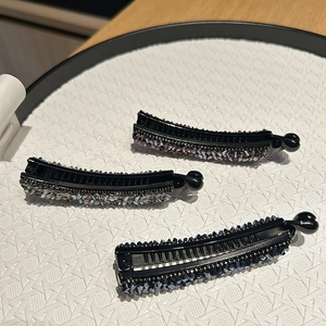 Barrettes banane étincelantes avec strass violets et bleus sur un plateau blanc