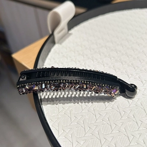 Détail du clip banane noir avec strass violets et dents antidérapantes pour la coiffure