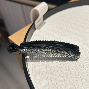 Gros plan d'une pince banane noire ornée de strass multicolores brillants sur un plateau