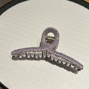 Close-up of lavender fabric texture and golden metal spring on large hair claw clip