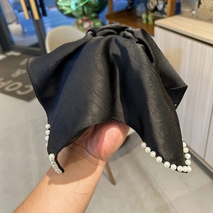 Détail d'un serre-tête en satin noir avec d'élégantes perles blanches et un joli nœud