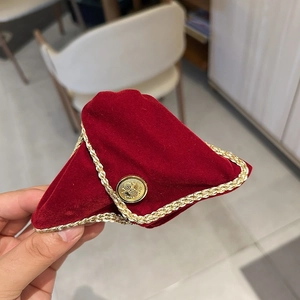 Detail view of burgundy velvet fabric with golden braided trim and relief button on headband