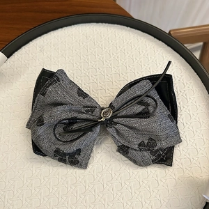 Close-up of retro silver fabric scrunchie with black dots and gold metal detail