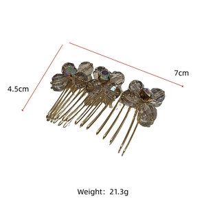 Detail view of gold metal hair comb with grey crystal flowers, 7cm by 4.5cm dimensions