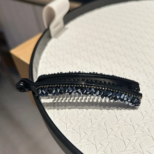 Gros plan d'une pince banane avec des strass bleu foncé sur un plateau de présentation blanc