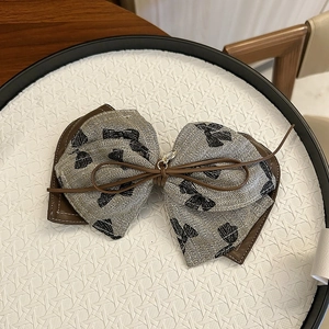 Close-up of the double-layer bow scrunchie with leather trim and gold pendant detail