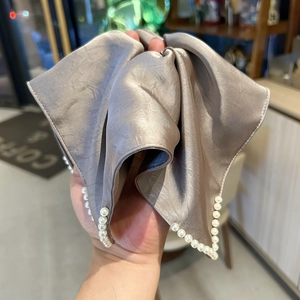 Détail d'un chouchou en satin argenté avec bordure en perles et aspect soie