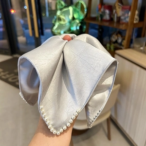 Gros plan d'un chouchou en satin argenté orné de perles blanches et de strass brillants