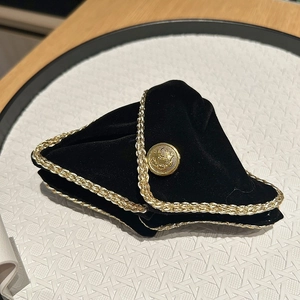 Detail of black velvet headband with gold braided trim and central embossed metal button