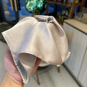 Gros plan d'un chouchou en satin champagne orné de perles blanches élégantes