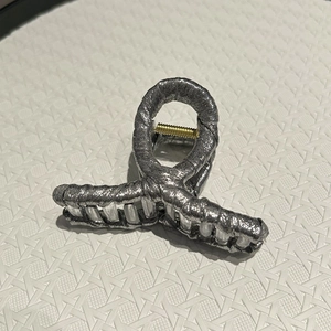 Detail of silver glitter fabric hair claw clip with golden spring mechanism and shiny finish