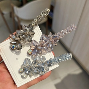 Vue détaillée de trois barrettes à fleurs en cristal en gris, rose et bleu clair