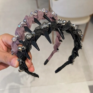 Dettaglio di cerchietto di lusso con punte nere, perline e texture in tessuto pieghettato