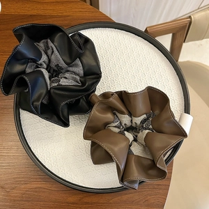 Dual-layer faux leather scrunchies in black and brown with elegant contrast stitching detail