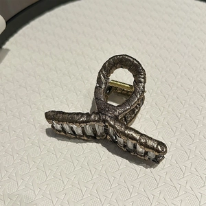 Detailed macro view of bronze large hair claw clip with pleated texture and metallic finish