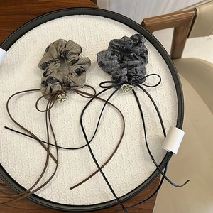 Chic scrunchies with polka dots and dark ribbons featuring gold heart pendants in a tray