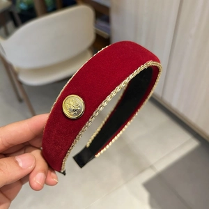 Close-up of red velvet headband with golden braided edge and embossed eagle button