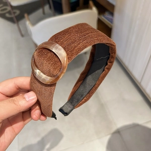 Close-up of brown suede headband featuring a textured fabric and amber resin ring detail