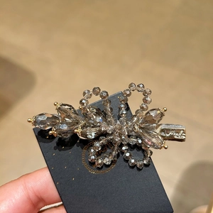 Close-up of grey crystal beaded hair clip with gold alloy details on black card