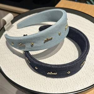 Detailed macro view of denim headbands with gold metallic studs and embossed letters