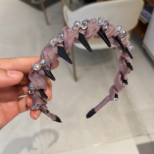 Dettaglio di cerchietto lilla in tessuto con perle di cristallo e borchie nere