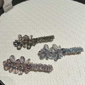 Détail de pinces à cheveux fleur en cristal en gris, bleu et violet sur fond blanc