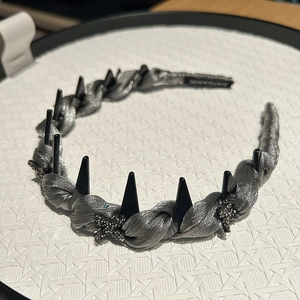 Detail of dark punk style headband with black rivets and stars on grey satin fabric