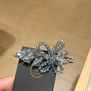 Detail of handcrafted blue crystal flower hair clip with golden beads on a handmade card