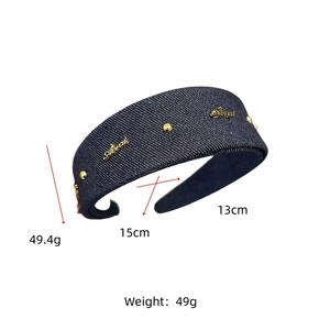 Detailed side view of dark blue denim headband featuring gold studs and metal branding