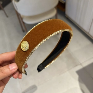 Detailed close-up of a burgundy velvet headband with gold braided trim and a round button