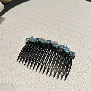 Dettaglio del pettine per capelli con squame di pesce blu e strass brillanti