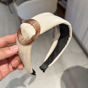 Detail of beige woven fabric headband featuring a translucent amber resin ring buckle decor