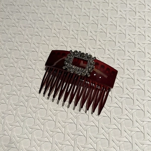 Macro detail of wine red resin hair comb with square rhinestone buckle decoration
