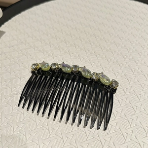 Dettaglio del pettine per capelli in cristallo con ciondoli a pesce cangianti e strass neri