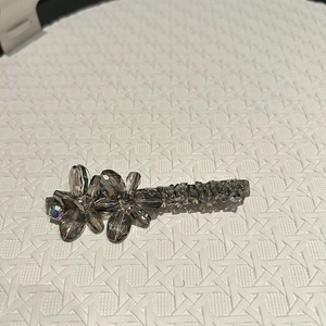 Détail de la pince à cheveux fleur en cristal étincelant avec pierres gris foncé sur blanc