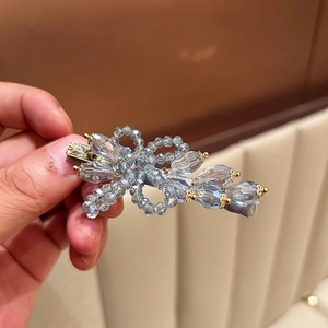 Macro shot of blue crystal flower hair clip with gold metal base for women's hairstyle