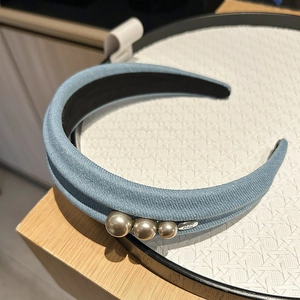 Détail d'un serre-tête en denim bleu clair orné de perles et d'une étiquette métal