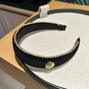 Detail of black velvet headband with gold braided chain trim and vintage emblem button