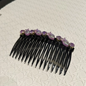Dettaglio di un pettine per capelli con cristalli viola e decorazione a forma di pesce