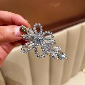 Detailed view of handmade blue crystal flower hair clip with golden metallic spring clip