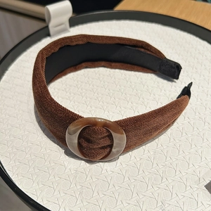 Close-up of brown velvet headband with a marble-textured ring on a white display tray
