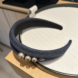 Détail d'un serre-tête en denim bleu foncé avec perles et étiquette métallique artisanale